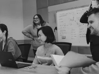 Group of people laughing and working together in a meeting.